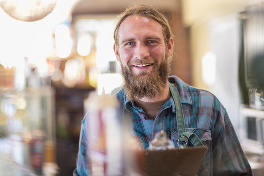 Caucasian server holding clipboard in cafe