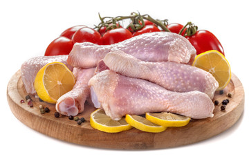 .Fresh chicken legs with tomatoes, lemon and spices, on a white background