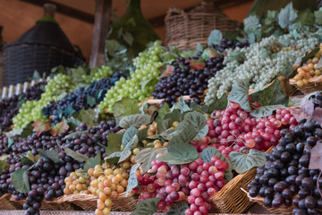 Bunch of Colorful Grapes in Wicker Basket on Wooden Shelf