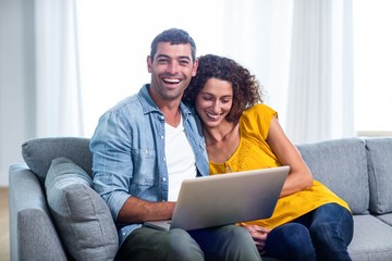 Young couple sitting on sofa and using laptop