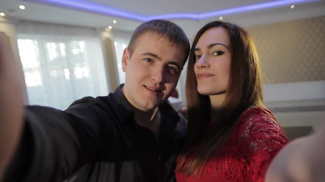 Beautiful young couple smiling in the room takes a selfie