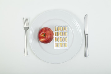 Vitamintabletten und Apfel