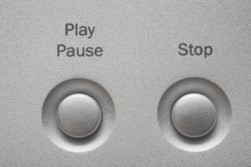 Macro of Play, Pause and Stop buttons on aluminum panel.