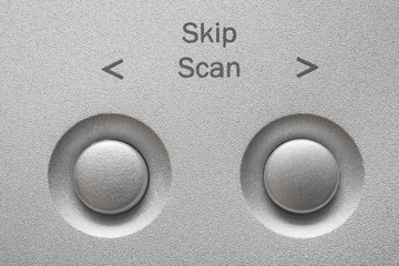 Macro of Skip, Scan buttons on aluminum panel.