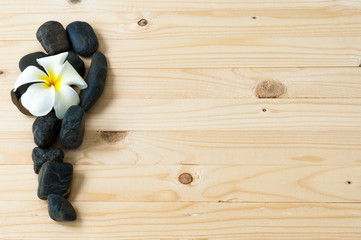 Obraz na płótnie Canvas Flower on group of black stone on wooden floor.