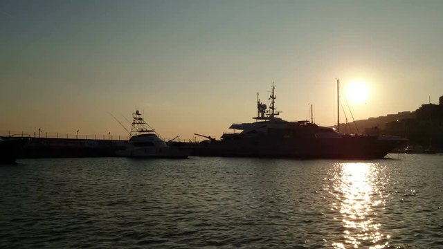 Luxury yachts docked in the port of Naples, Italy, at sunset
