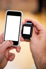Mans hand holding a smart watch and a mobile phone