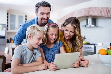 Fototapeta na wymiar Parents and kids using digital tablet in kitchen