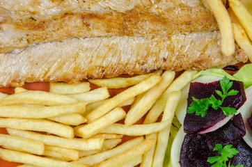 pork on a clay plate with fries