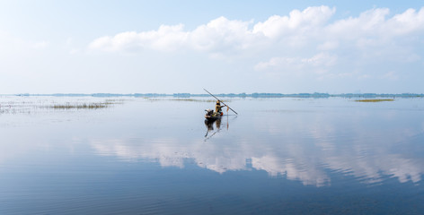 Fisherman on boat at wet land.