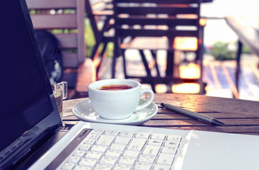 vintage color tone, laptop and cup of coffee on the table coffee shop [blur and select focus background]