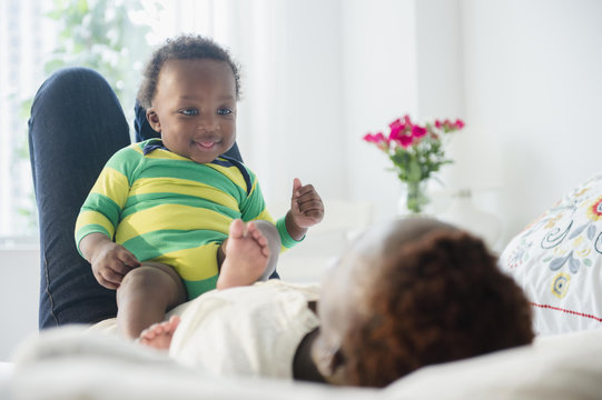 Mother Playing With Baby Boy On Bed