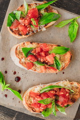 Bruschetta with tomatoes and basil on the parchment  top view