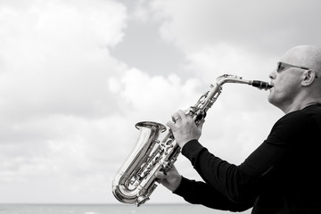 Fototapeta na wymiar Saxophonist playing on saxophone on blue sky background