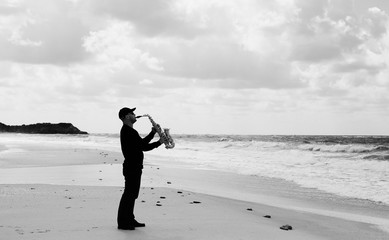 Saxophonist playing on saxophone on blue sky background