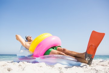 Man lying on lilo wearing rubber ring
