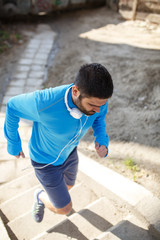 Man in blue shirt running up the stairs. Cross fit training.City environment.