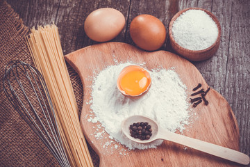 Pasta spaghetti with flour, egg on old wooden background