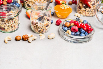 Muesli mix with nuts and berries in glass jars on light background, close up. Healthy lifestyle and Clean food concept.