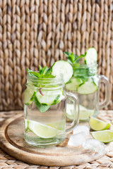 Infused water with cucumber, lime, ice and mint on rustic background. Detox drink, selective focus.Close up.