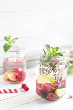 Summer refreshment drink. Water with cucumber, lime, ice and mint on rustic background. Pink Detox.