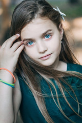Spring fairy. Portrait of beautiful little girl with brownish blond hair and blue eyes standing outdoor on natural background. © videnko