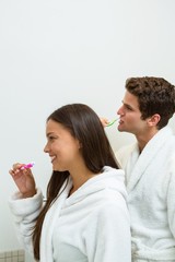 Couple in bathrobe brushing their teeth in bathroom