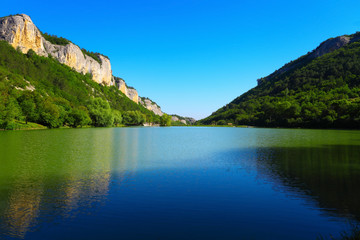 Fototapeta na wymiar Mountain lake between the rocks and green trees