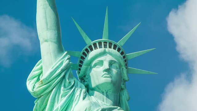 Statue of Liberty - Close-up with Tourists in the Crown Observation Deck Pointing through the Windows on a Sunny Day with White Clouds Moving in a Blue Sky Background