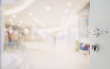 opened white door to shopping mall interior with bokeh as background