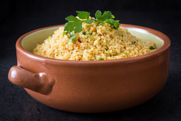 Couscous with vegetables on black stone
