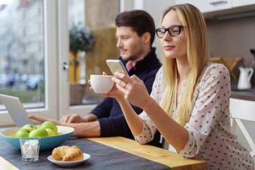 paar sitzt beim frühstück mit laptop und mobiltelefon