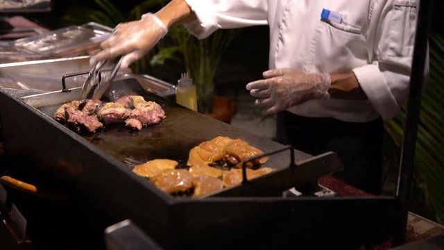 Chefs prepare clams and fish in a restaurant in the open air in the evening.