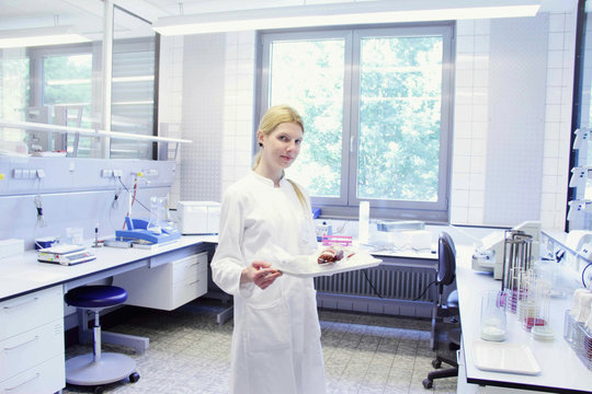 Scientist with tray looking at camera
