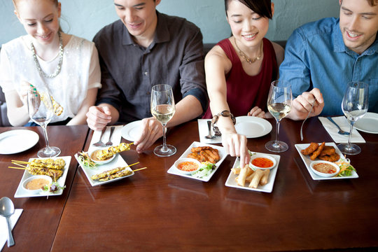 Four Friends Eating Food In Restaurant