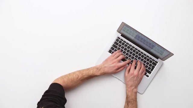 Man types on a laptop on his desk  . Upview