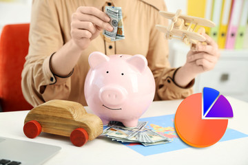 Business accounting concept. Woman putting dollar banknotes into piggy bank.