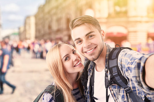 Young couple of travelers taking selfie on street in city