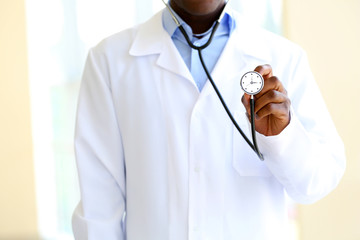 Fototapeta premium Male doctor holding stethoscope with clock