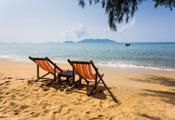 sun beach chairs on shore near sea.