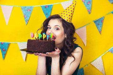 Beautiful caucasian girl blowing candles on her cake. Celebration and party. Having fun. Young...