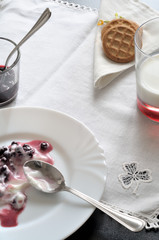 colazione per due, frutti di bosco con yogurt e un bichiere di latte con biscotti, su una tovaglietta bianca ricamata, formato verticale
