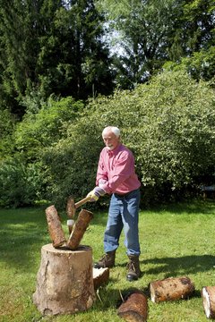 Senior man chopping logs in garden