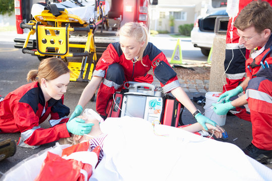 Three paramedics with patient on stretcher wearing oxygen mask