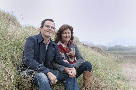 Couple watching from sand dune, Thurlestone, Devon, UK