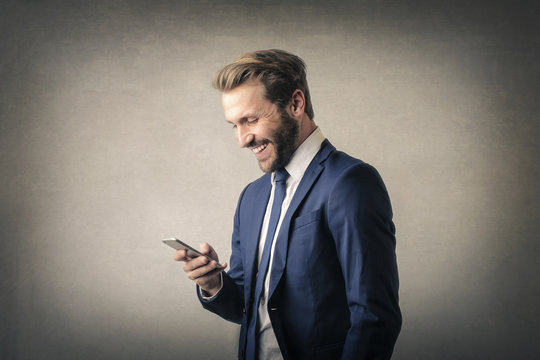 Laughing businessman with smartphone