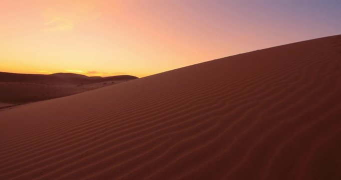 Donna risale una d'una di sabbia al tramonto infuocato
