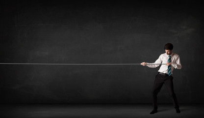 Businessman pulling rope on grey background