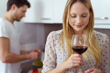 frau genießt ein glas rotwein zuhause in der küche