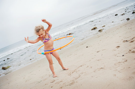 Young girl with hoolahoop on the beach